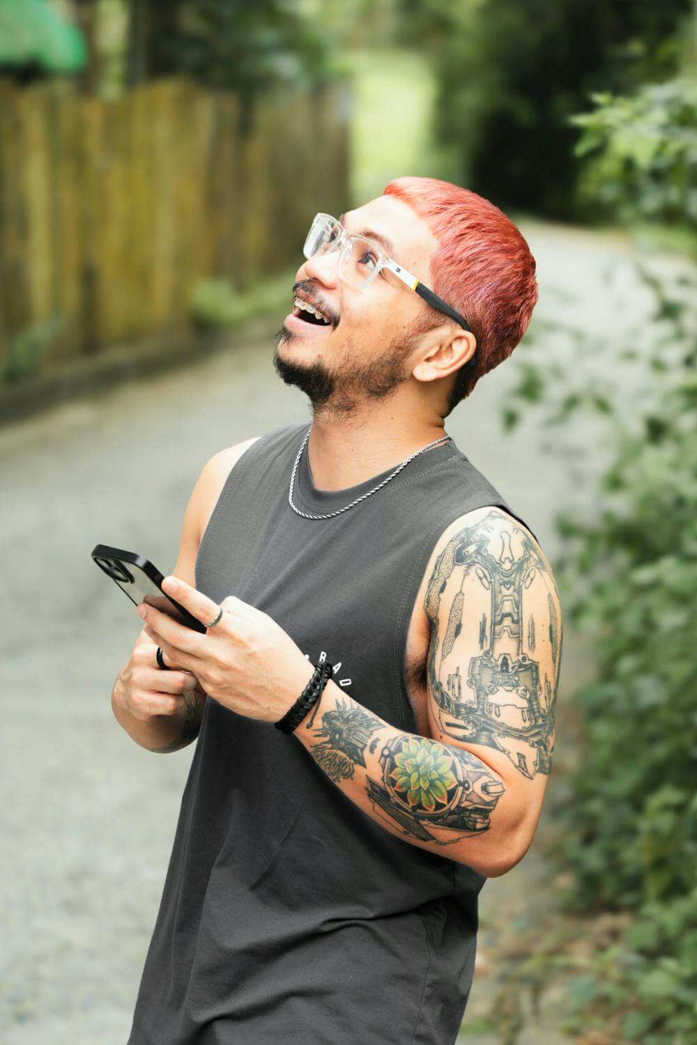 Photo of joyful tattooed man with smartphone outdoors.