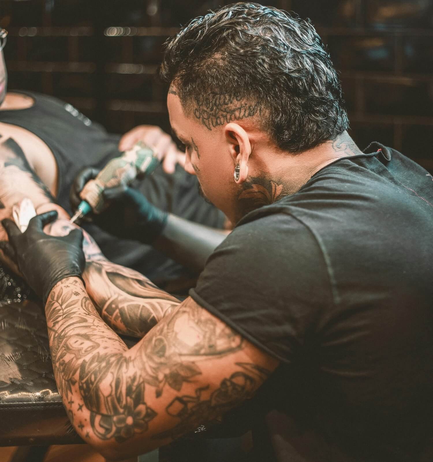 Tattoo artist working on arm of man